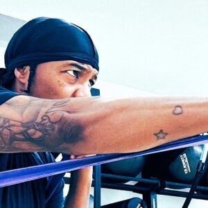 Rahsh aka Cold Work the Pro Boxer wearing a black head wrap training with a resistance band, extending their arm in a punching motion inside a gym.